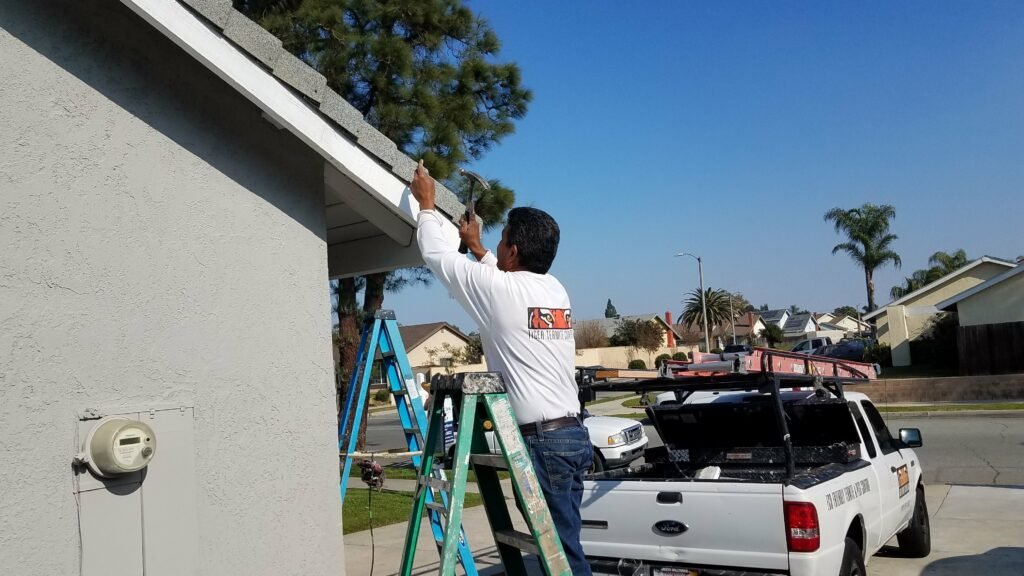 Termite repair technician on a ladder fixing roof shingles.